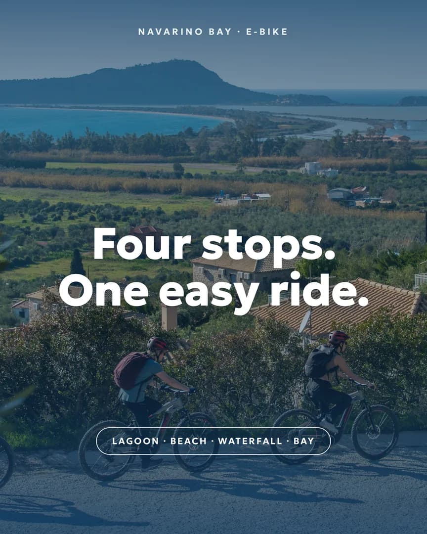 Two e-bikers ride down toward Navarino Bay's lagoon and coastline in golden light.
