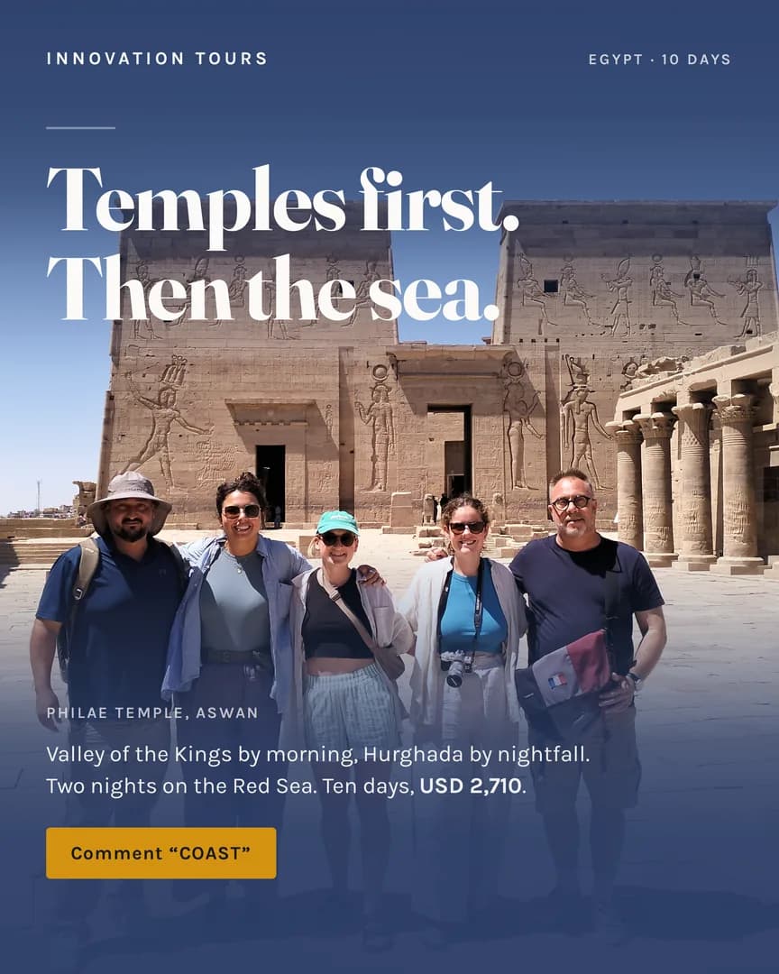 Philae Temple's stone pylons at Aswan, five travelers standing in front in bright sun.