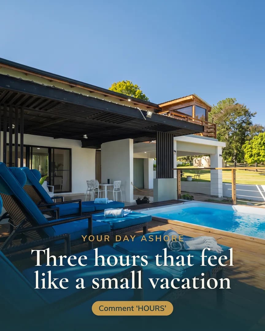 Blue lounge chairs and rolled white towels on a wooden deck by a pool at a mountainside spa.