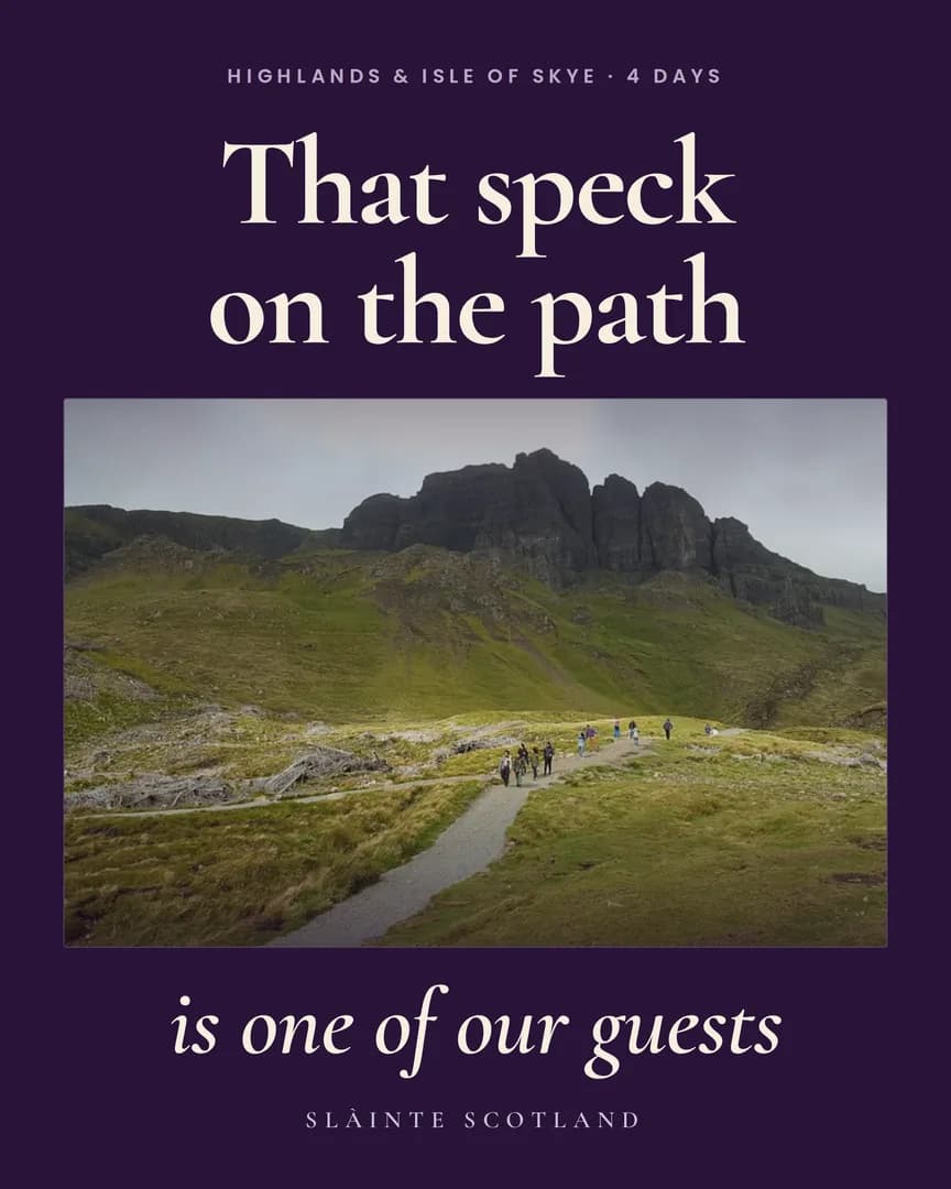 Walkers small on a gravel path below a large dark rocky ridge on the Isle of Skye.