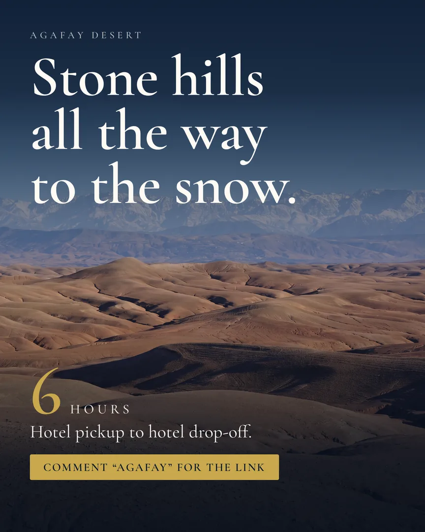 Rolling stone hills of the Agafay desert with the snow-capped High Atlas on the horizon.